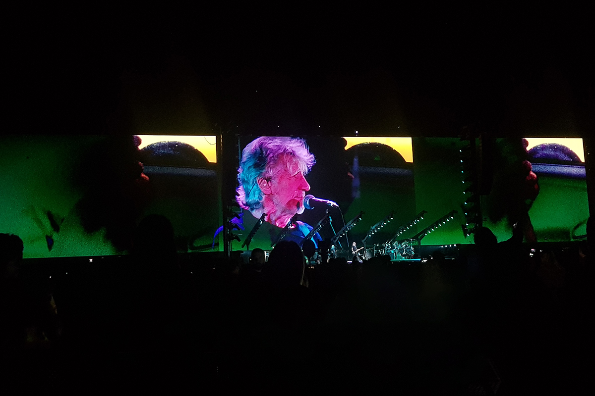 Roger Waters cantando para um estádio lotado.