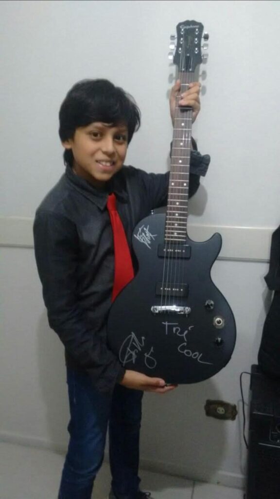 Fã que subiu ao palco com Green Day em Curitiba e a guitarra que ganhou de presente. Foto: acervo pessoal.